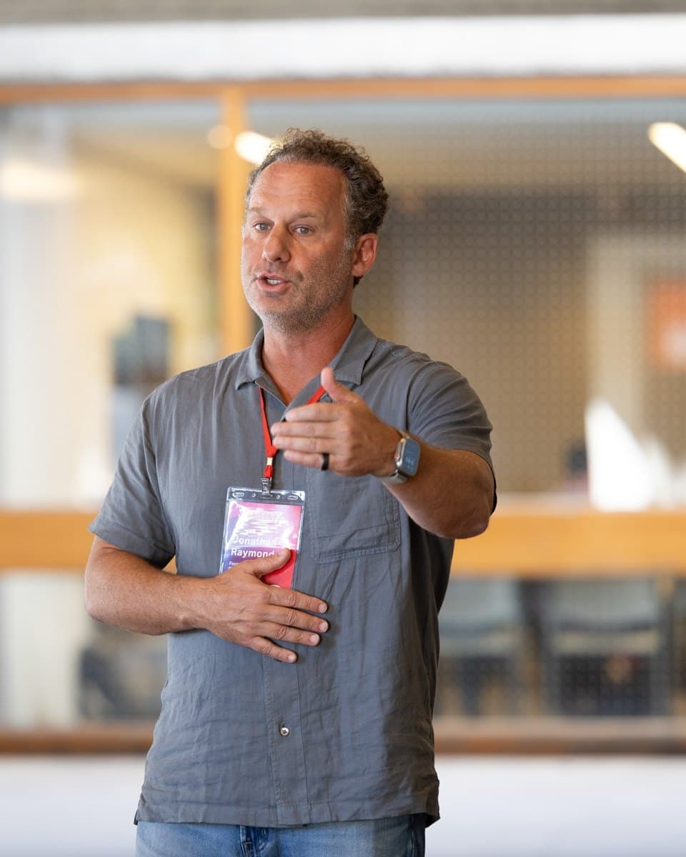 Jonathan Raymond speaking with one hand resting on his stomach