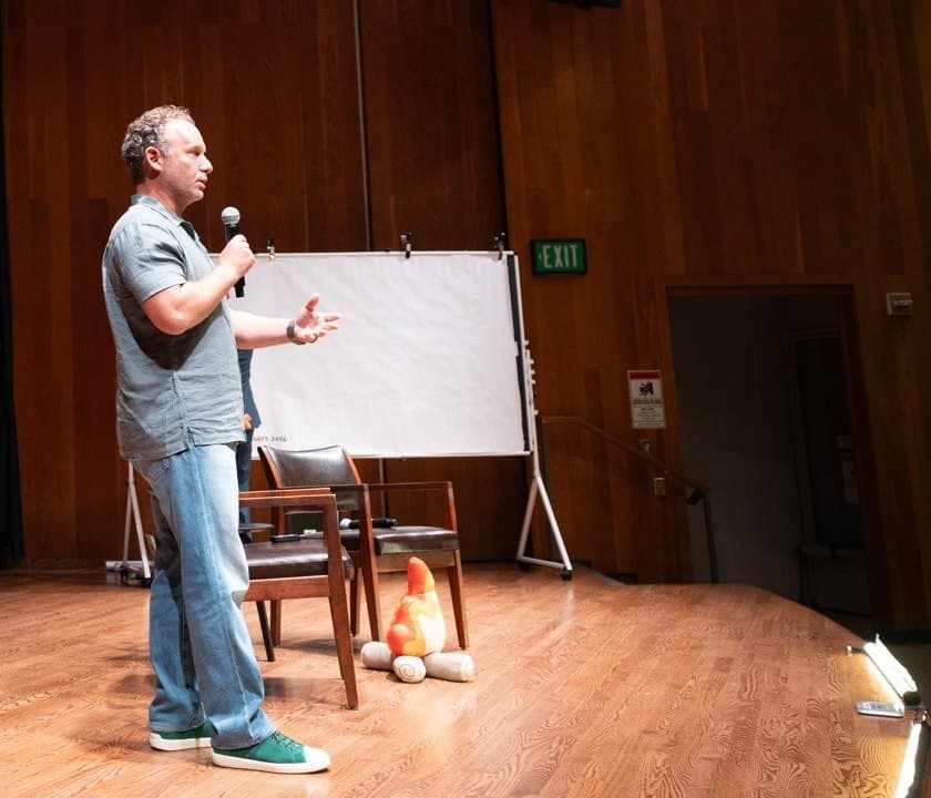 Jonathan Raymond speaking on a conference stage with a microphone