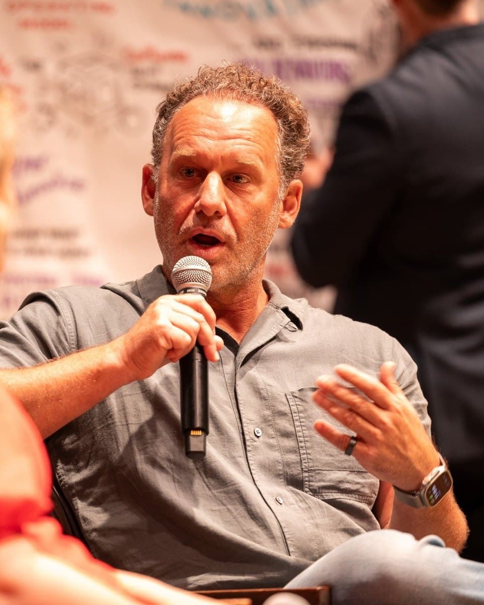 Jonathan Raymond speaking into a microphone on a conference panel